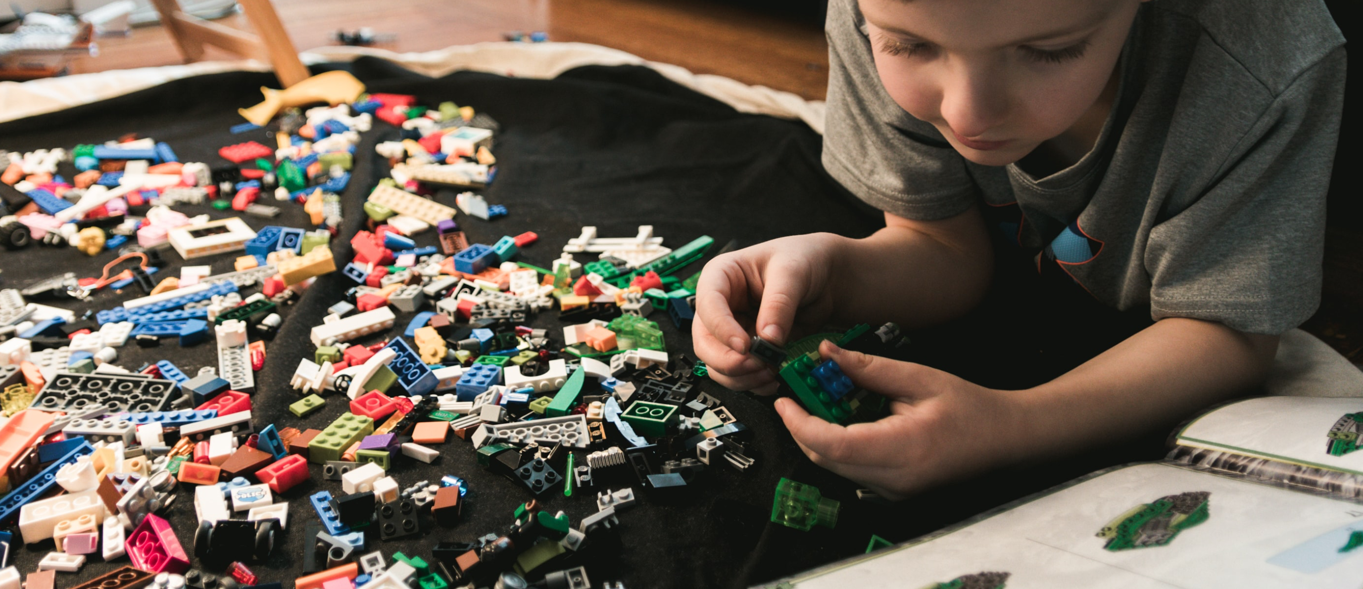 Child playing on the floor with numerous LEGO bricks